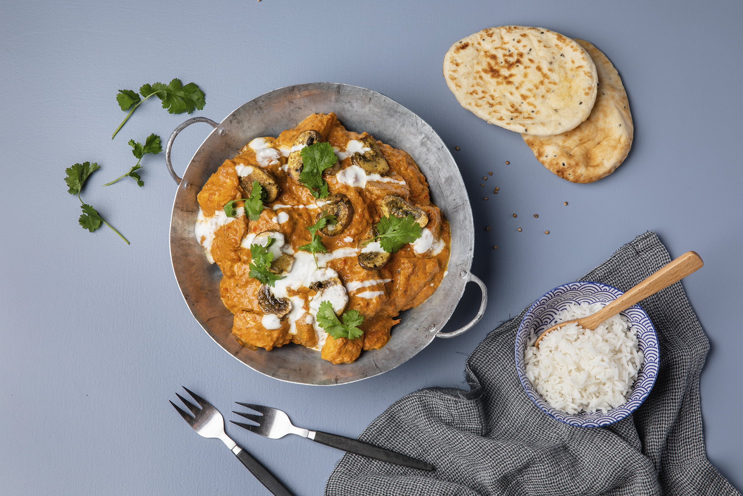 Kuvassa on padassa tikka masalaa. Tausta on sininen.